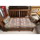 An Ercol country style two seater settee with stick back floral tapestry upholstery