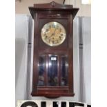 A mahogany cased wall clock with brass dial and bevelled glass