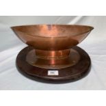 An Arts & Crafts boat shaped copper vessel mounted on oval mahogany plinth