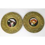 A 19th century pair of porcelain saucers with embossed brass mounts, decorated with women in