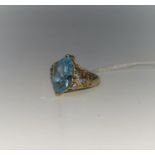 A yellow metal dress ring stamped '375' set with marquise cut pale blue stone with 3 small