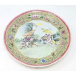 A Chinese famille jaune wall plaque depicting central scene of warriors on horse back 34cm diameter
