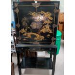 An early 20th century oriental cabinet on stand, black lacquered with gilt decoration of bridge