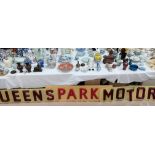 A large 'Queens Park Motors' garage sign