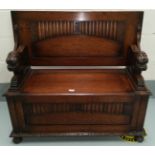 An oak monks bench with panelled decoration and grape carving, lion arm supports, on bun feet,