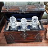 A small wood and metal bound dome top box containing three cut glass scent bottles