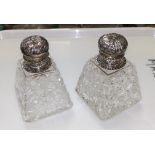 A pair of conical cut glass salts with embossed silver lids