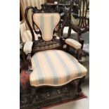 A late Victorian dark mahogany armchair with extensive carved decoration and cabriole legs in