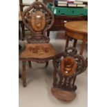 A carved "Black Forest" hall chair with Tyrolean scene marquetry panels to the seat and back and a