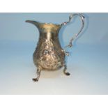 A hall marked silver milk jug with relief decoration of flowers on three raised feet Chester 3.8oz