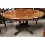 An oval Victorian figured walnut and marquetry quarter veneered looe table on 4 turned columns and 4