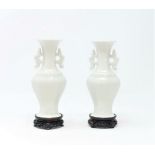 A pair of Chinese blanc de chine vases on wooden stands with double handles, 14cm