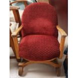A 1930's low seat cross framed armchair in red moquette