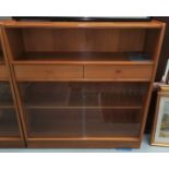 A mid 20th century teak bookcase by Nathan with central drawers and sliding doors, height 106 cm x