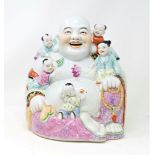 A large Chinese porcelain figure of a laughing Buddha seated with children climbing on him, height