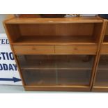 A mid 20th century teak bookcase by Nathan with central drawers and sliding doors, height 106 cm x