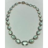 An aquamarine colour faceted stone necklace with yellow metal mounts (tests as 9 carat)