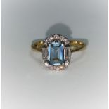 An 18 carat gold dress ring set emerald cut aquamarine flanked by 2 baguette cut and 10 small