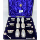 A cased 12 piece barrel shaped cruet set comprising six salts, six pepper pots and six salt spoons