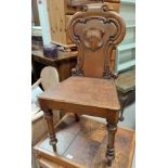 A pair of carved oak hall chairs with shield backs