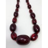 A cherry amber Bakelite colour necklace with alternating cloudy oval beads and clear faceted