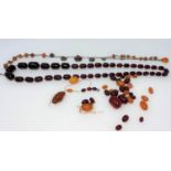 A cherry amber Bakelite coloured necklace with clear oval beads and a selection of loose amber and