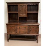 A 1930's oak Welsh dresser with central cupboard and open shelves over 2 doors and 2 drawers, on