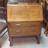 A 1930's golden oak bureau with fall front and 2 drawers, on bulbous legs