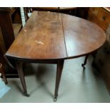 A Georgian mahogany dining table with oval drop leaf top, on turned legs and castors, 140 cm