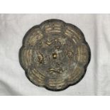 A Chinese bronze scalloped circular plaque with mythological creatures to the centre and linear