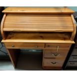 A modern pine roll top pedestal desk with four drawers bellow