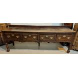 A mid 18th century oak dresser base with 4 frieze drawers, shaped apron and turned legs, later