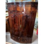 A 19th century mahogany bow front corner cupboard with 2 arched panelled doors over single drawer