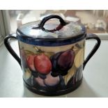 A Moorcroft biscuit barrel, wisteria pattern against a dark blue group, impressed and signed (lid