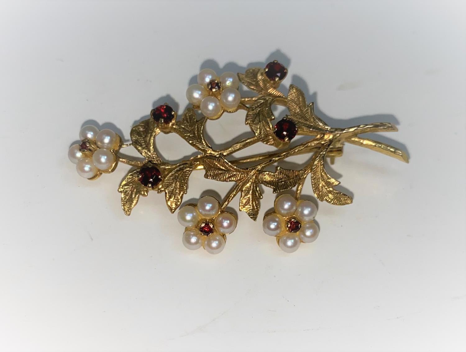 A 9 carat hallmarked gold brooch, floral spray with 4 flowerheads set seed pearls and garnets, the
