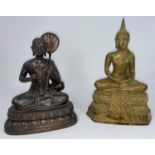 An oriental bronzed Buddha figure in seated lotus position holding a leaf fan, and a similar metal