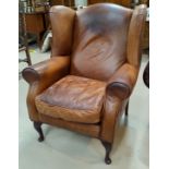 A traditional style wing backed armchair in tan hide