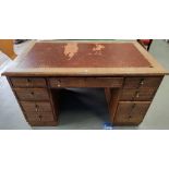 A 1930's oak kneehole writing desk with inset leather top, 8 pedestal and 1 frieze drawer, with