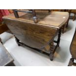 A 1930's oak gate leg dining table with oval drop leaf top, on barley twist legs