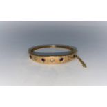 An Edwardian hinged bangle set alternately with 4 diamonds and 3 sapphires, unmarked tests as 14 g