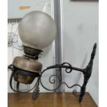 A brass and wrought iron oil lamp, wall mounted, with shade