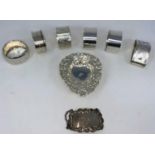 Six various silver napkin rings; an embossed silver bon-bon dish; a silver "Sherry" bottle label (