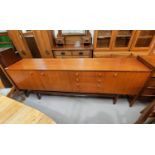 A mid-20th century teak long low sideboard, comprising: cupboard to each end, a full front