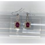 A pair of Art Deco style white metal earrings, each set 28 diamonds and an oval cabochon ruby -