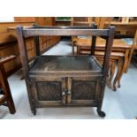 An oak 2 tier tea trolley with carved cupboard under