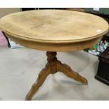 An oval pine pedestal table with two hoop back chairs.