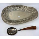 An Indian silvered metal serving dish and spoon with extensive embossed decoration, inc elephants