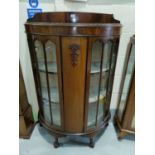 A mahogany bow front corner cupboard with double glazed doors on ball and claw feet