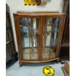 A mahogany two door display cabinet with double shelves and a mirrored back.