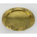 An oval planished brass tray with embossed Art Nouveau relief decoration to the rim, stamped